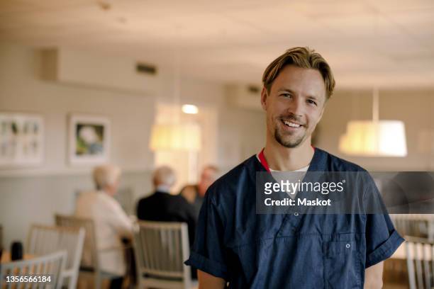 portrait of smiling male caregiver at nursing home - nurse portrait stock pictures, royalty-free photos & images