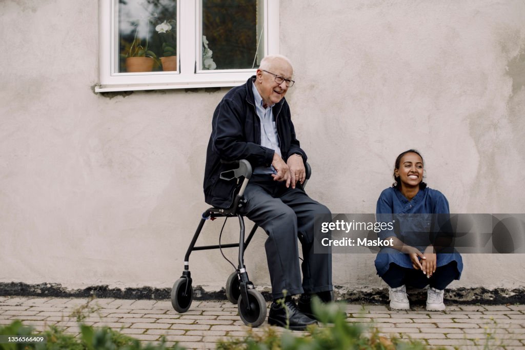 Senior man and female caregiver looking away at footpath