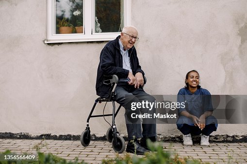 Senior man and female caregiver looking away at footpath Senior man and female caregiver looking away at footpath