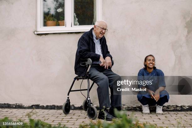 senior man and female caregiver looking away at footpath - retirement community building stock pictures, royalty-free photos & images