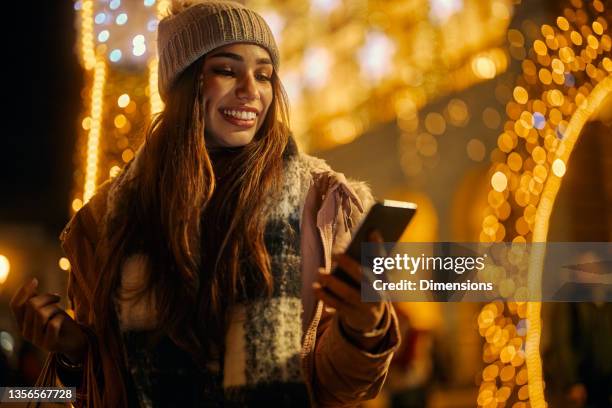 lächelnde frau beim einkaufen und telefonieren im freien - advent stock-fotos und bilder