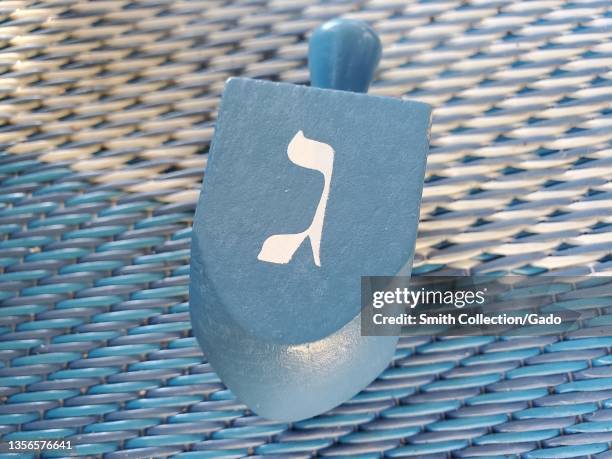 White dreidel, used during the Hanukkah holiday in Judaism, is visible on a white and blue surface, Lafayette, California, November 17, 2021.