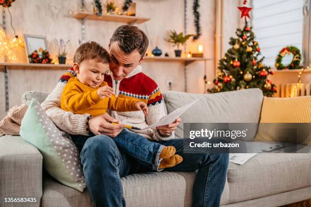 baby boy helping dad manage home finances at home - christmas budget stock pictures, royalty-free photos & images