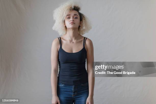 confident young woman wearing black tank top against white background - huvudet bakåt bildbanksfoton och bilder