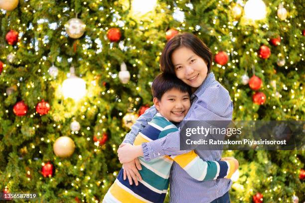 asian mother and son hugging and enjoying christmas lights - bovenlichaam stockfoto's en -beelden