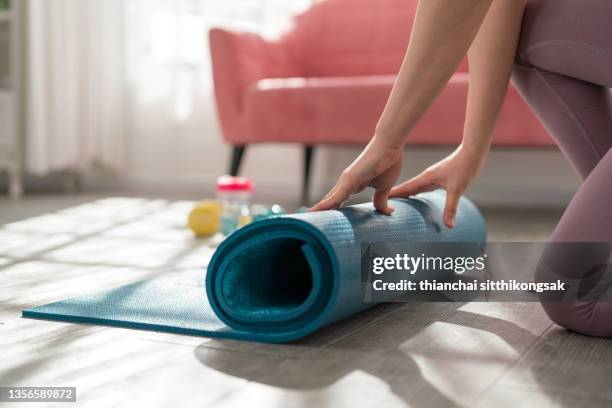 cropped shot of unrecognizable woman rolling up her yoga mat after class end. - tapis de sol photos et images de collection