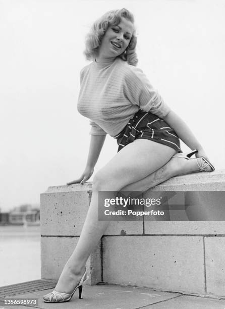 English glamour model and actress Sabrina , wearing shorts and a sweater, circa 1955.