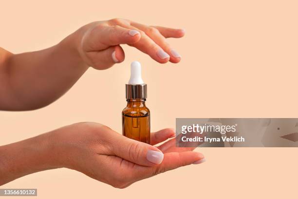 woman hands hold beauty product facial serum or essential oil . - argan oil stock-fotos und bilder