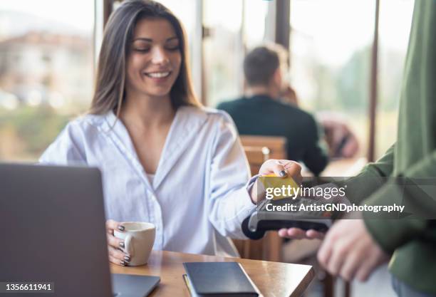 businesswoman making credit card payment while working in cafe - customers pay with contactless cards stock pictures, royalty-free photos & images