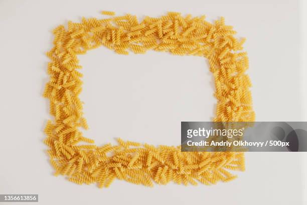 spiral pasta on a white background forming a frame around top view - carbohydrate food type stock pictures, royalty-free photos & images