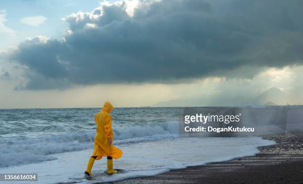 storm clouds, high waves and man in yellow raincoat. - extreme weather events stock pictures, royalty-free photos & images