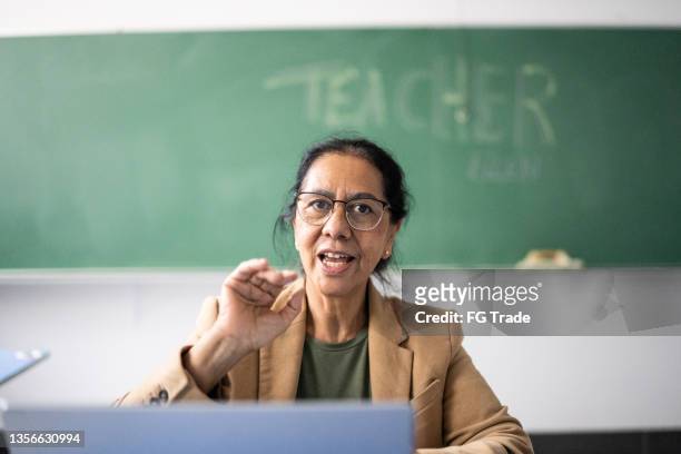 senior teacher doing an online class on the laptop in the classroom - one woman only videos stock pictures, royalty-free photos & images