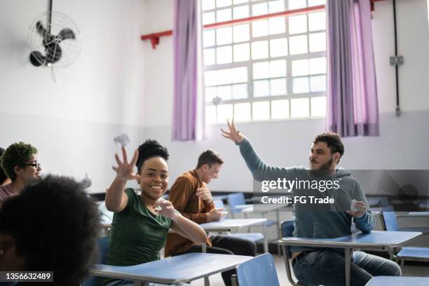 schüler kämpfen mit zerknitterter papierkugel im klassenzimmer in der schule - classroom riot stock-fotos und bilder