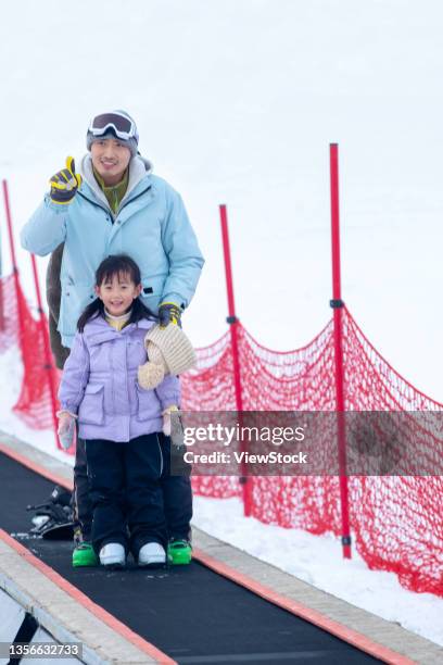 father and daughter skiing stadium stood on the conveyor belt - chute ski fotografías e imágenes de stock