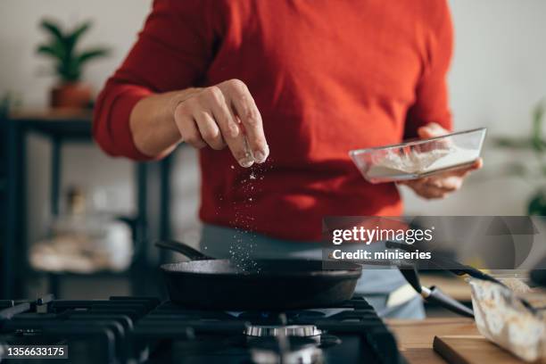 close up of anonymous man adding salt to a meal - strooisels stockfoto's en -beelden