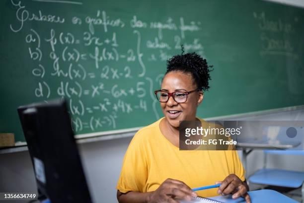 profesor usando portátil para hacer una clase en línea / video - sólo con adultos fotografías e imágenes de stock