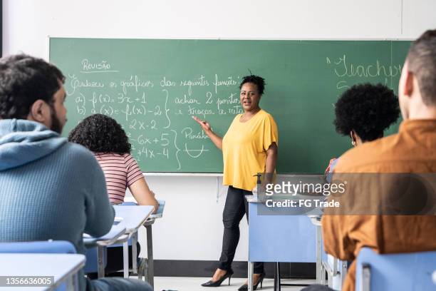 lehrer im gespräch mit schülern während des unterrichts in der schule - black teacher stock-fotos und bilder