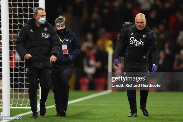 Watford medical staff who assisted a fan in the crowd walk back to the bench during a break in play during the Premier League match between Watford...