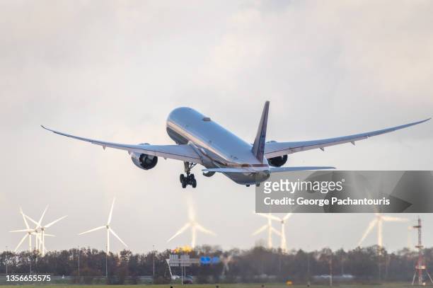 passenger aircraft taking off with wind turbines in the background - luftfahrzeug stock-fotos und bilder