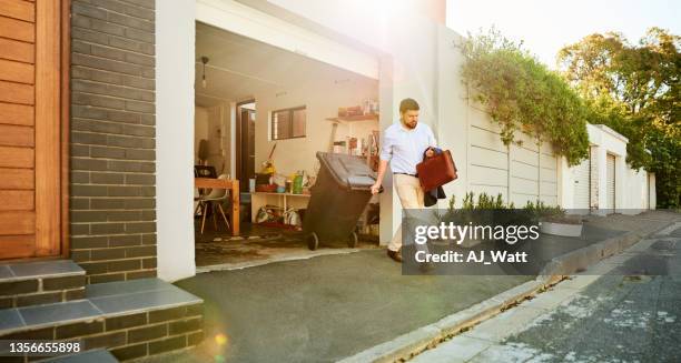 man pulling trash bin out of his garage while going to work - special waste stock pictures, royalty-free photos & images