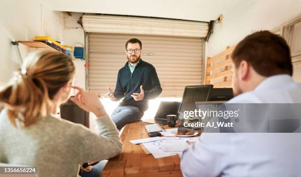three people discussing their startup business in a garage - small office stock pictures, royalty-free photos & images