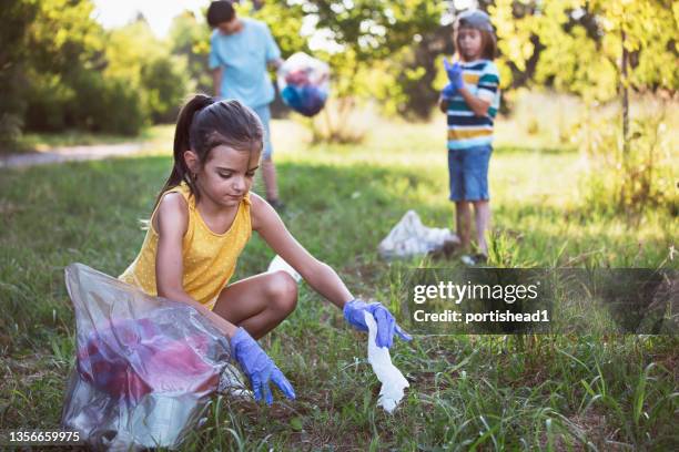 little girl, volunteer picking up trash in the park - environmental cleanup stock pictures, royalty-free photos & images