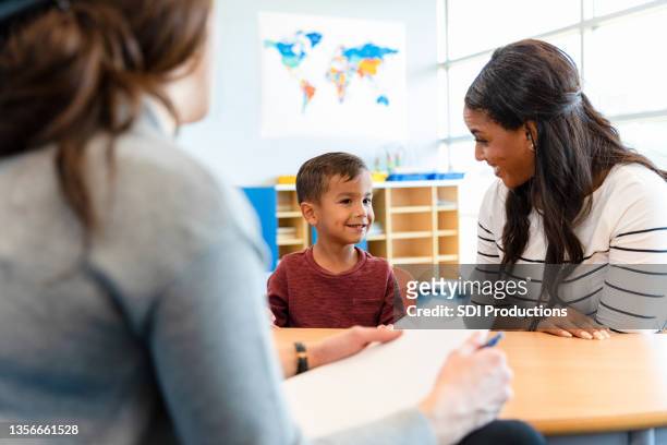 un psychologue pour enfants parle avec un jeune garçon et sa mère - teacher student photos et images de collection