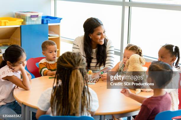 smiling teacher teaches children about the solar system - preschool stock pictures, royalty-free photos & images