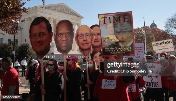 Demonstrators carry large photographic cut-outs of members of the U.S. Supreme Court as the justices hear arguments in Dobbs v. Jackson Women's...