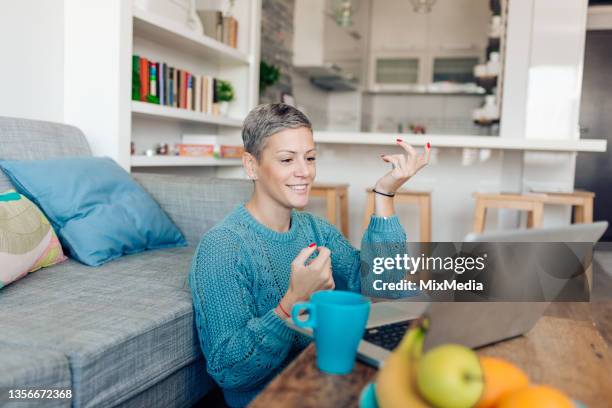 mujer que tiene una reunión de negocios en línea mientras trabaja desde casa - una mujer de mediana edad solamente fotografías e imágenes de stock