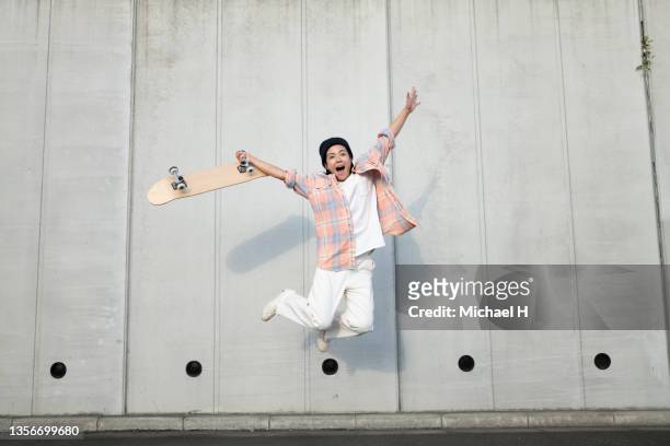 portrait of a female jumping skateboarder. - only japanese stock pictures, royalty-free photos & images