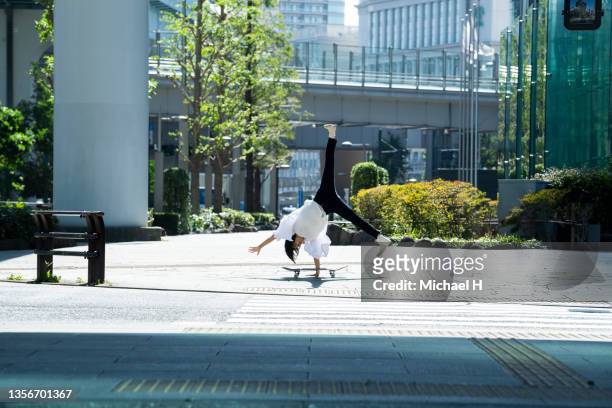 a skateboard with a woman cartwheeling in an empty city. - mittag stock-fotos und bilder