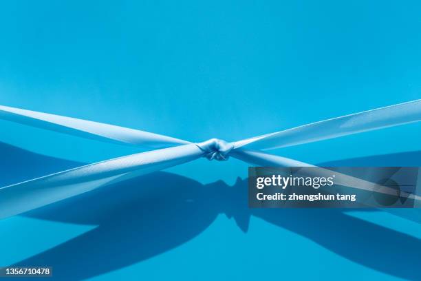 the blue ribbons are pulled together tightly - pulling stock pictures, royalty-free photos & images
