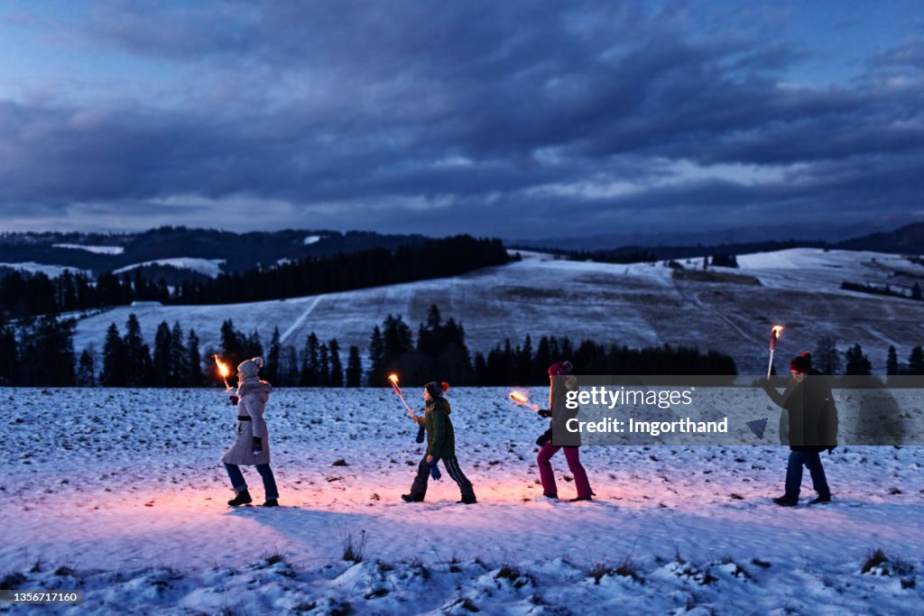 Family walking in on hill with flaming torches