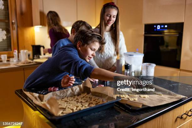 mother and three kids making cookies in kitchen - tulband stockfoto's en -beelden