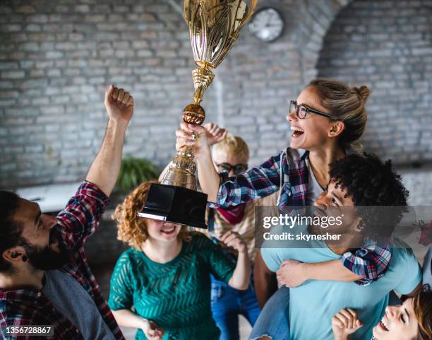 large group of happy creative people celebrating getting a trophy at casual office. - cas awards stock pictures, royalty-free photos & images