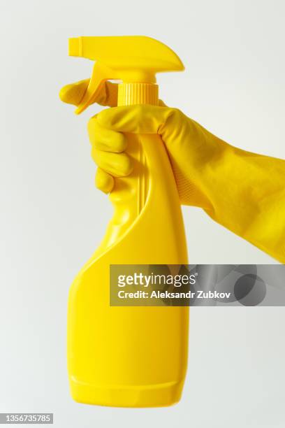 a sprayer, sanitizer or cleaner in the hands of a woman. a cleaner in rubber gloves holds a spray with detergent and cleaning agent. cleaning company, home visit. professional cleaning after repair or construction. prevention from coronavirus. copy space. - rubber gloves stockfoto's en -beelden