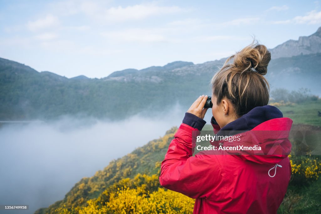 Young woman watches sunrise over mountains