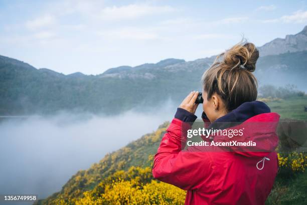 young woman watches sunrise over mountains - binoculars imagens e fotografias de stock