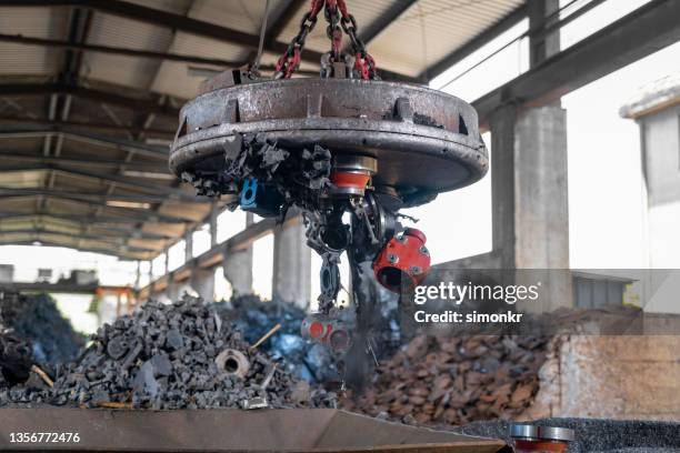 chatarra liberada en una trituradora de metal utilizando un imán industrial - chatarra fotografías e imágenes de stock