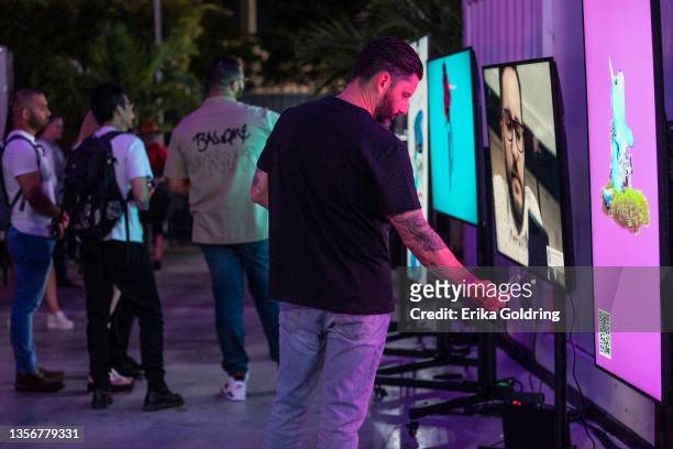 Guest interacts with the NFT collection on display at presented by Marshland, Magnus and FloodFM.com at Maps Backlot during Art Basel Miami on...