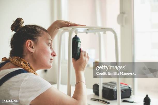 woman using electric screwdriver in her workshop - restoring chair stock pictures, royalty-free photos & images