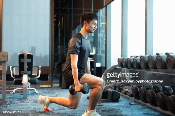 young man doing lunges with dumbbells in gym - fitness man gym stockfoto's en -beelden