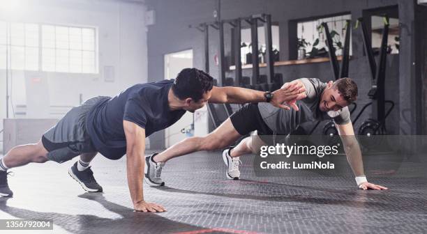 scatto di due uomini che fanno flessioni condividendo un cinque alto in palestra - hi five gym foto e immagini stock