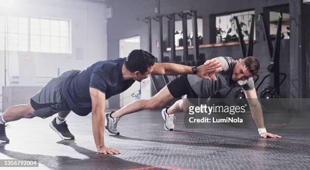 shot of two men doing pushups sharing a high five at the gym - male studio shot stock pictures, royalty-free photos & images