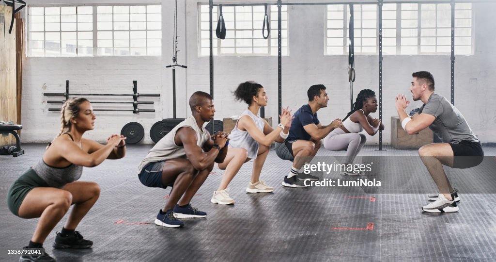 Shot of a group of young people exercising under the watchful eye of their trainer at the gym