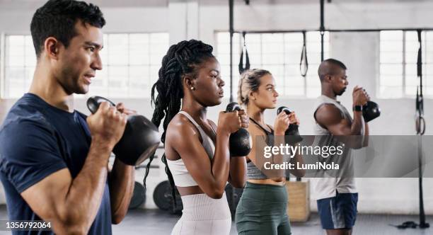 aufnahme einer gruppe junger leute, die im fitnessstudio gemeinsam kettlebells heben - krafttraining stock-fotos und bilder