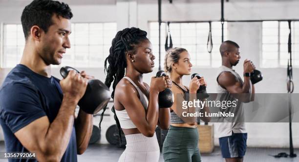 shot of a group of young people lifting kettlebells together at the gym - weight lifting imagens e fotografias de stock