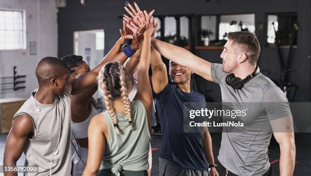 shot of group of gym buddies sharing a high five at the gym - hi five gym stockfoto's en -beelden