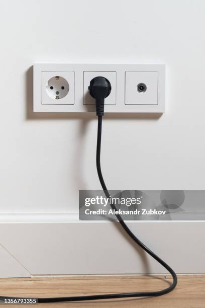 electrical outlet, cable and electrical plug on a white wall background. the concept of technology. a copy of the space for text and labels. - enchufe fotografías e imágenes de stock